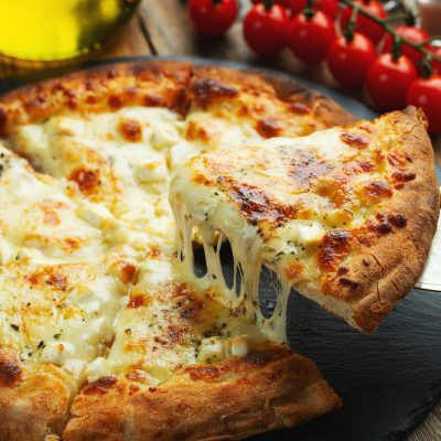 A slice of hot Italian pizza with stretching cheese. Pizza four cheeses with basil.